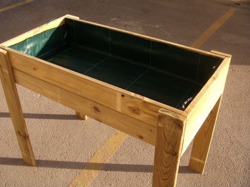 Mesa de cultivo de madera montada sobre patas con hortalizas