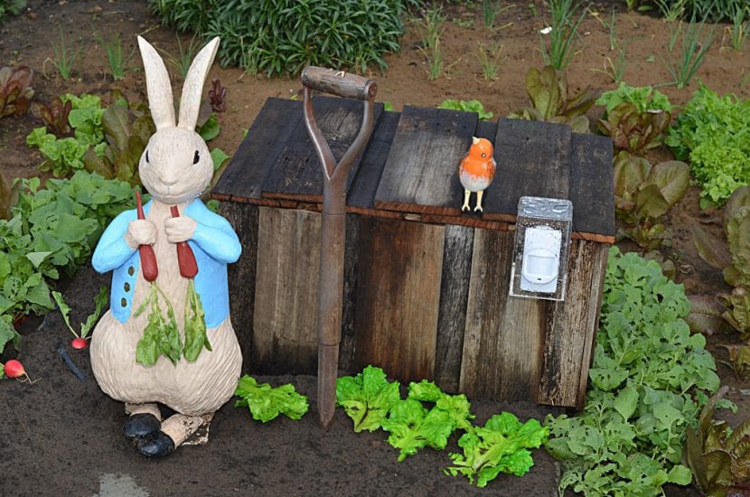 Figura decorativa de conejo entre las plantas del jardín
