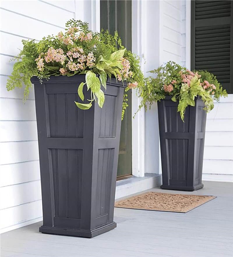 Composición de plantas sobre soportes altos en la entrada de una casa